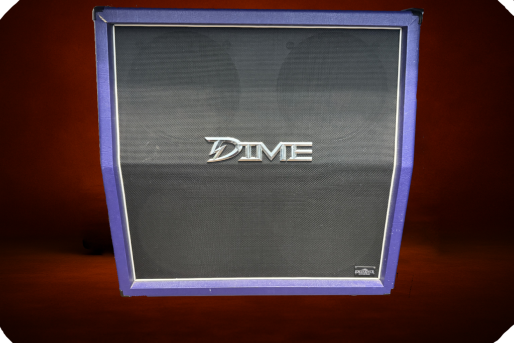 Dime signature guitar speaker cabinet with purple tolex, black grille cloth, chrome Dime logo, and visible speaker outlines, photographed against a dark orange studio background.